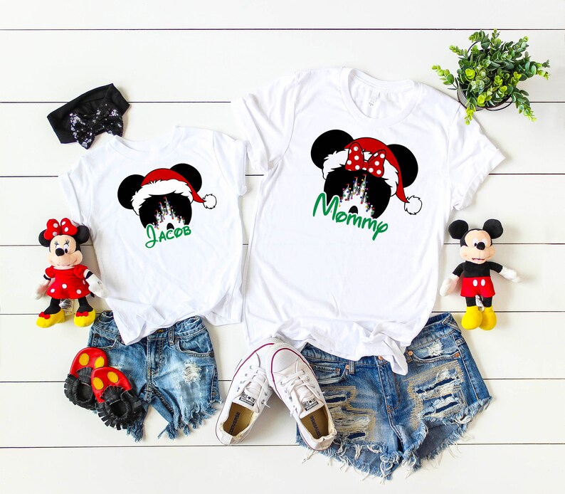 May include: White t-shirts with a Christmas Mickey Mouse design. The adult shirt says "Mommy" and the child's shirt says "Jacob".