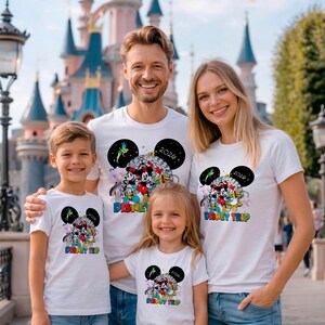 May include: White t-shirts with a colorful Disney graphic featuring Mickey Mouse, Minnie Mouse, and other characters. The shirts have the text "Disney Trip 2020" in a rainbow font. The family is smiling in front of a castle.
