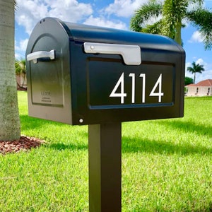 May include: Black mailbox with a silver handle and white numbers "4114" on the front. The mailbox is mounted on a black post.