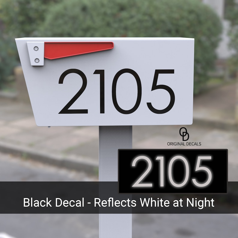 May include: White mailbox with a red flag and black reflective house number decals. The mailbox has the number 2105 on it. The decals reflect white at night.