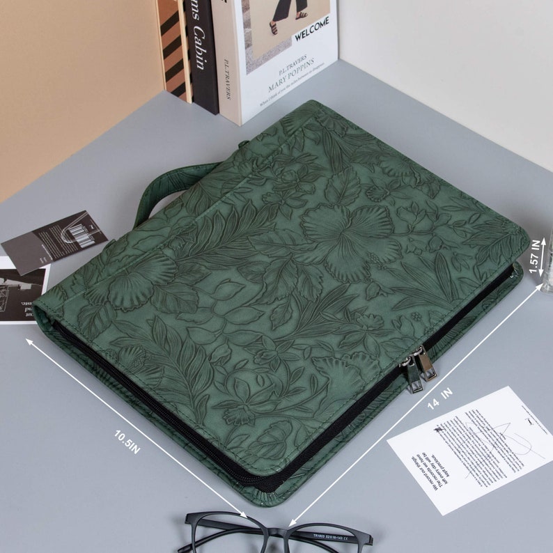 May include: A green leather zippered portfolio with a floral embossed design. The portfolio measures 14 inches by 10.5 inches by 1.57 inches.