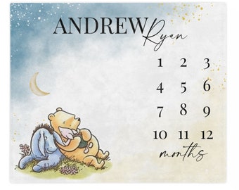 May include: A Winnie the Pooh and Piglet baby milestone blanket with a blue and yellow watercolor background. The blanket features a crescent moon, stars, and the text "ANDREW Ryan" and "1 2 3 4 5 6 7 8 9 10 11 12 months".