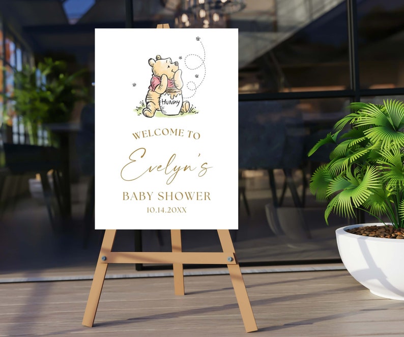 May include: A white welcome sign with a Winnie the Pooh illustration. The sign says "Welcome to Evelyn's Baby Shower 10.14.20XX".