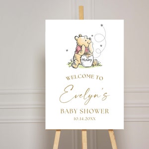 May include: A Winnie the Pooh baby shower welcome sign with a cartoon illustration of Winnie the Pooh holding a honey pot. The sign says "Welcome to Evelyn's Baby Shower 10.14.20XX".