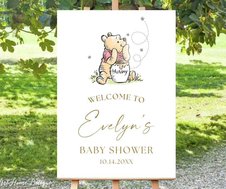 May include: White welcome sign with a Winnie the Pooh illustration. The sign says "Welcome to Evelyn's Baby Shower 10.14.20XX".