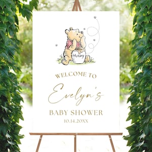 May include: White welcome sign with a Winnie the Pooh illustration. The sign says "Welcome to Evelyn's Baby Shower 10.14.20XX".