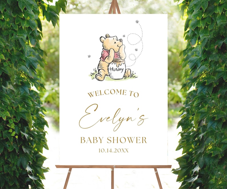 May include: White welcome sign with a Winnie the Pooh illustration. The sign says "Welcome to Evelyn's Baby Shower 10.14.20XX".