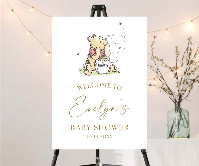 May include: A white welcome sign with a Winnie the Pooh illustration. The sign says "Welcome to Evelyn's Baby Shower 10.14.20XX".