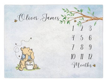 Könnte beinhalten: Eine Baby-Meilenstein-Tabelle im Winnie-Puuh-Design mit einem blauen und weißen Aquarell-Hintergrund. Die Tabelle zeigt Winnie Puuh, der ein Honigglas hält, und eine Biene, die über ihm fliegt. Die Zahlen 1 bis 12 sind in einer Spalte auf der rechten Seite der Tabelle aufgelistet, mit dem Wort "Monate" unter den Zahlen. Der Name "Oliver James" steht oben auf der Tabelle.