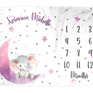 Puede incluir: Una manta de beb&eacute; blanca con una luna creciente rosa y morada y un elefante gris sentado sobre ella. La manta est&aacute; decorada con estrellas rosas y grises y el texto "Arianna Michelle" y "1 2 3 4 5 6 7 8 9 10 11 12 Meses".