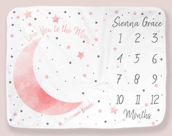 May include: A white baby blanket with a pink watercolor moon and stars. The blanket has the text "Love You to the Moon -and-Back" and "Sienna Grace 1 2 3 4 5 6 7 8 9 10 11 12 Months".