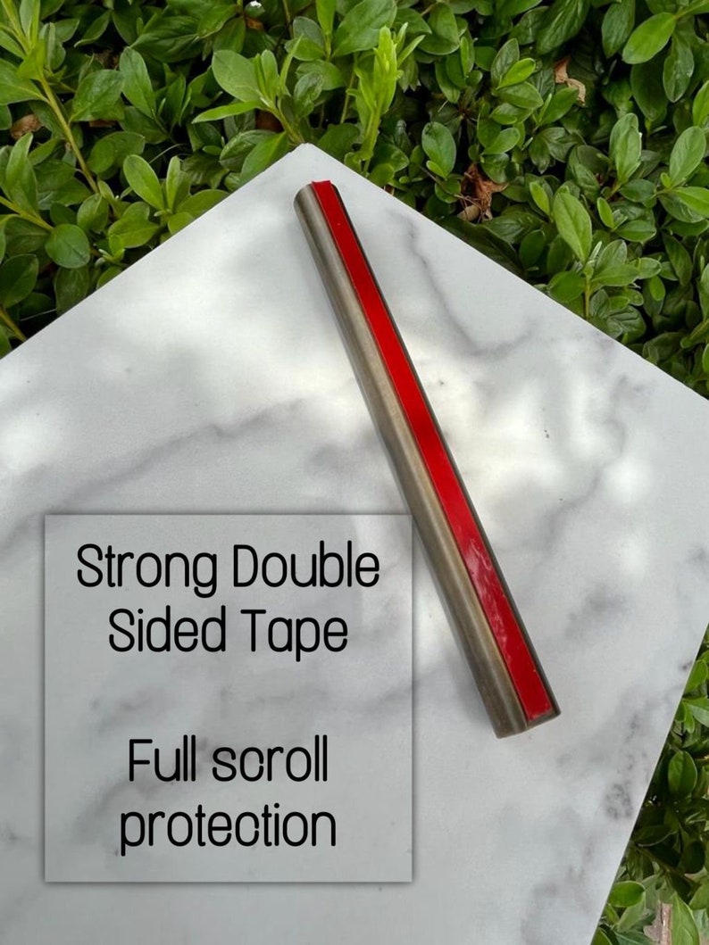 Pode incluir: Um rolo de fita adesiva de dupla face resistente sobre uma superf&iacute;cie de m&aacute;rmore branco. A fita &eacute; vermelha e tem um suporte prateado. O texto "Strong Double Sided Tape" e "Full scroll protection" &eacute; vis&iacute;vel na imagem.