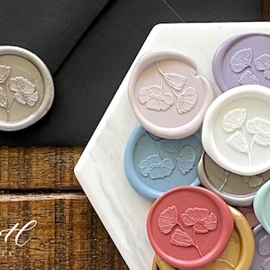 Beautiful self-adhesive wax seal stamps in the design, Summer Bloom. Summer Bloom design showcases 3 flowers at various stages of bloom. Available in 22 colors and perfect for wedding invites, escort cards, gift wrapping, or sealing a special note.