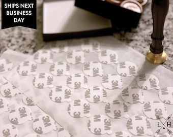 May include: A close-up of a sheet of white paper with multiple round, white adhesive stickers. The stickers have the 3M logo printed on them. The text "SHIPS NEXT BUSINESS DAY" is visible in the top left corner of the image.