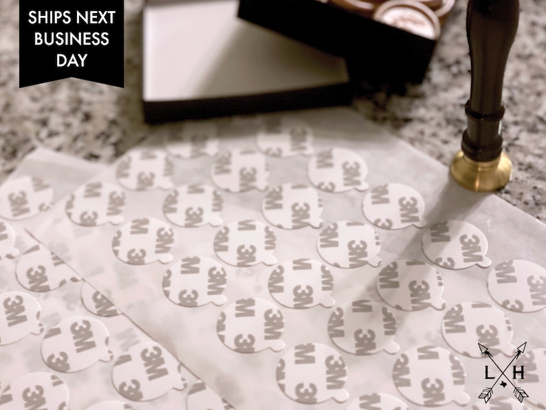 May include: A close-up of a sheet of white paper with multiple round, white adhesive stickers. The stickers have the 3M logo printed on them. The text "SHIPS NEXT BUSINESS DAY" is visible in the top left corner of the image.