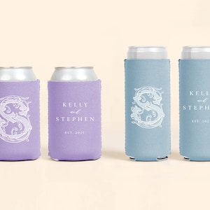 May include: Four beverage can coolers in shades of purple and blue. Two purple coolers and two blue coolers are visible. Each cooler has a white decorative initial and the names "Kelly and Stephen" with the year "2025".