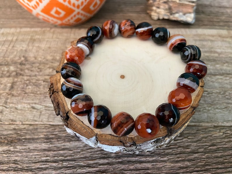 Beads are round and faceted. Three natural red and black banded agate beaded stretch bracelets