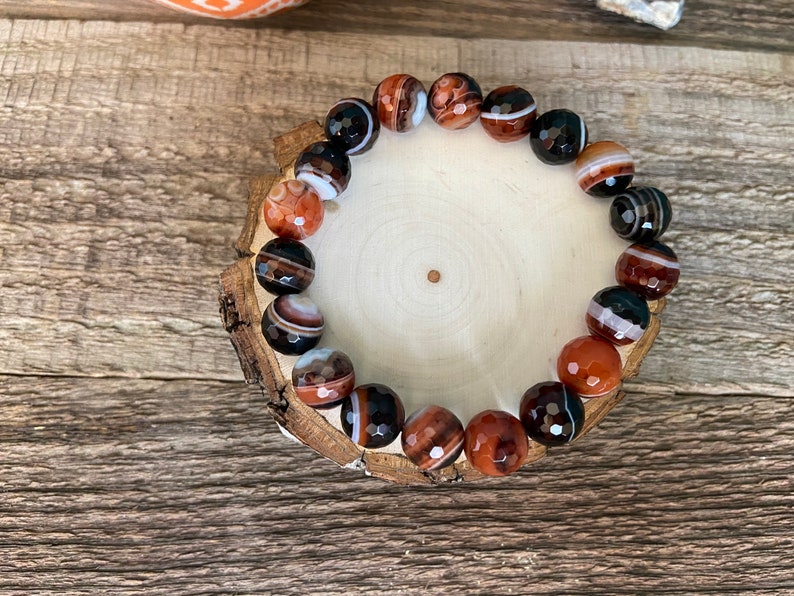Beads are round and faceted. Three natural red and black banded agate beaded stretch bracelets