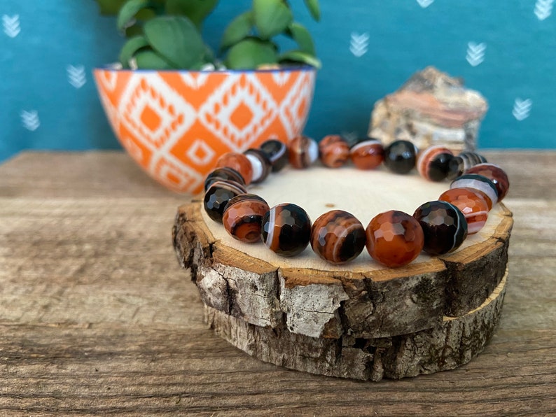 Beads are round and faceted. Three natural red and black banded agate beaded stretch bracelets