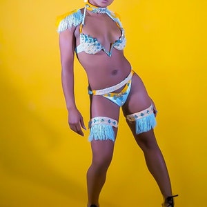 May include: A woman wearing a blue and yellow costume with fringe. The costume includes a bra top, a skirt, and leg garters. She is wearing clear heels with black laces.