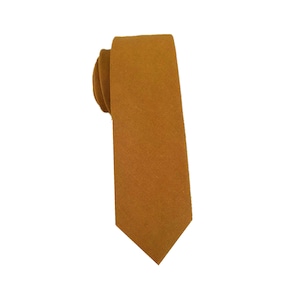 May include: A solid mustard yellow skinny tie. The tie is made of a textured fabric.