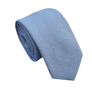 May include: A light blue linen tie. The tie is rolled up and ready to be worn.