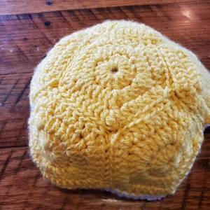 May include: A yellow crocheted hat with a white crocheted brim.