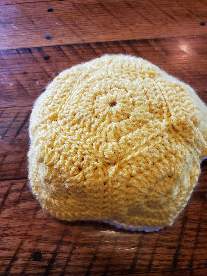 May include: A yellow crocheted hat with a white crocheted brim.
