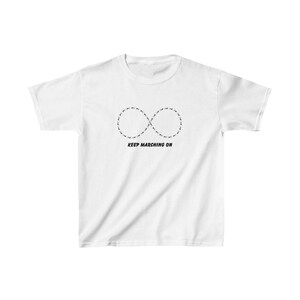 May include: White t-shirt featuring a black infinity symbol design made of small dots. Below the symbol, the text "KEEP MARCHING ON" is printed in black. The shirt is made of a soft, comfortable material.