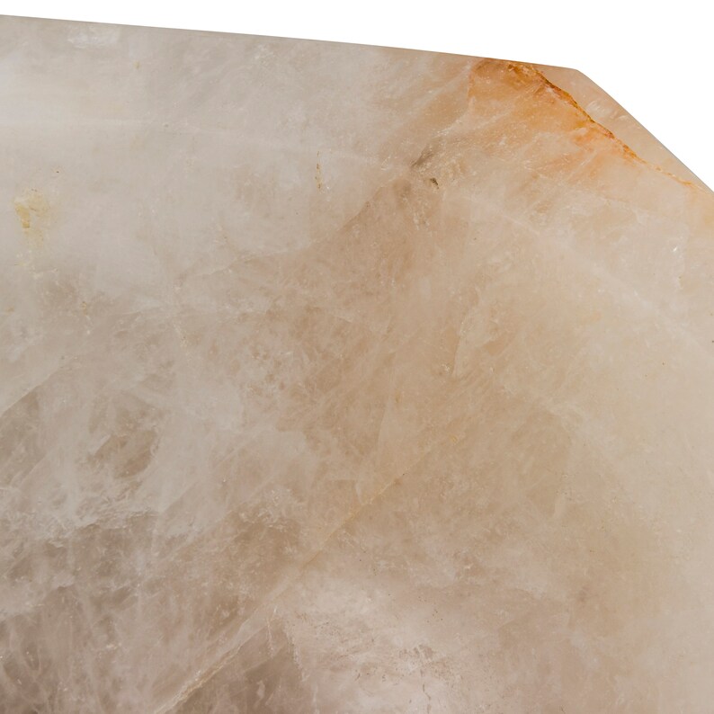 Może przedstawiać: Zbliżenie na przezroczysty, nieregularny kryształ w jasnobrązowym kolorze o szorstkiej, fakturowanej powierzchni.