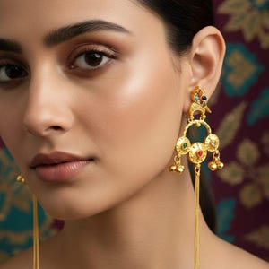 Puede incluir: Pendientes dorados con detalles intrincados. Los pendientes presentan un diseño similar a un pájaro en la parte superior, con piedras preciosas de colores y cadenas colgantes. Los pendientes tienen un diseño circular con pequeñas campanas colgantes.