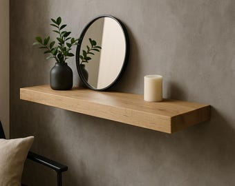 May include: A light oak floating shelf with a black framed round mirror, a black vase with greenery, and a white candle. The shelf is mounted on a gray wall, creating a minimalist decor aesthetic.
