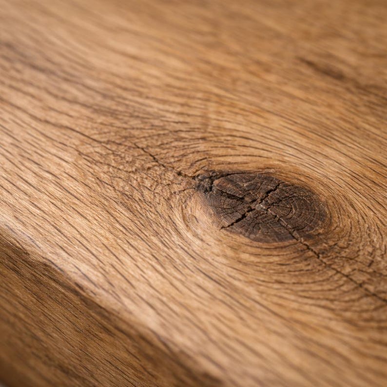 May include: Close-up of a section of light brown wood with a prominent knot. The wood grain is visible, with natural lines and textures. The knot is dark brown and cracked, adding to the rustic appearance.