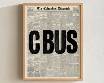 May include: Framed print featuring a vintage newspaper background with the bold black letters "CBUS" in the center. The top of the print reads "The Columbus Dispatch" in a serif font. The frame is a light wood color.
