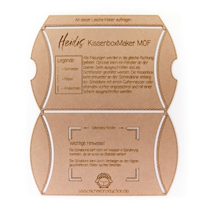 Könnte beinhalten: Eine braune Pappvorlage zum Basteln einer Kissenbox. Die Vorlage enthält Anweisungen zum Schneiden, Falten und Zusammenbauen der Box. Der Text auf der Vorlage lautet "Heidis KissenboxMaker MOF" und beinhaltet eine Legende mit Anweisungen zum Schneiden, Falten und Anritzen. Die Vorlage enthält auch einen Warnhinweis, dass die Vorlage nicht mit Wasser in Berührung kommen sollte.