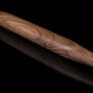 May include: A brown wooden rolling pin with a tapered end. The rolling pin has a natural wood grain pattern.