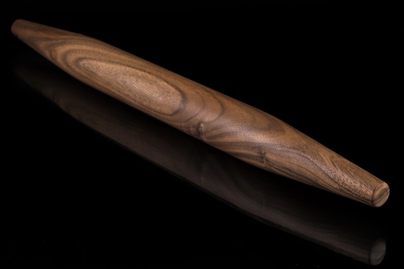 May include: A brown wooden rolling pin with a tapered end. The rolling pin has a natural wood grain pattern.