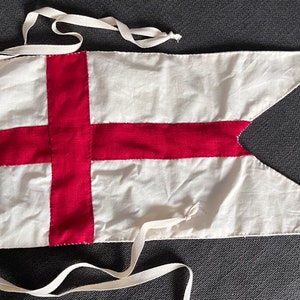 Könnte beinhalten: Eine weiße Flagge mit einem roten Kreuz, ein traditionelles Symbol Englands. Die Flagge hat zwei weiße Bänder, die oben befestigt sind.