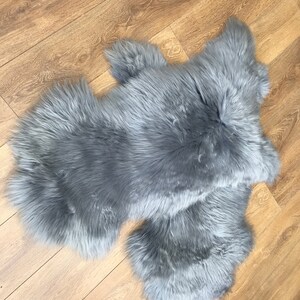 May include: A gray faux fur rug with a long pile. The rug is made of two pieces that are joined together.