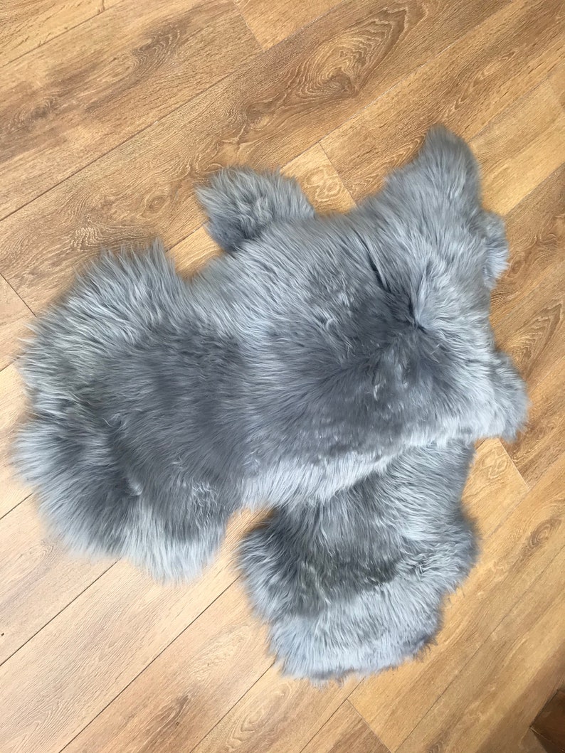 May include: A gray faux fur rug with a long pile. The rug is made of two pieces that are joined together.