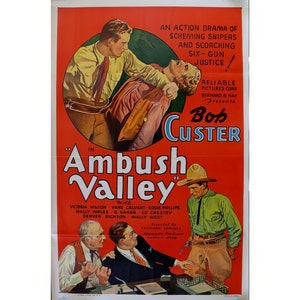 May include: A vintage movie poster for the film "Ambush Valley" starring Bob Custer. The poster features a red background with a scene of a man holding a woman in a chokehold. The text "Ambush Valley" is in large, bold letters at the bottom of the poster.