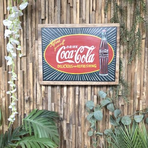 May include: A framed Coca-Cola sign featuring a red oval with white script reading "Coca-Cola". The sign also includes the phrases "Refresh yourself" and "Delicious and Refreshing". A Coca-Cola bottle is on the right.