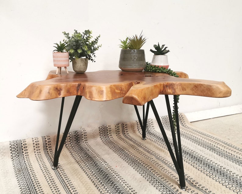Pu&ograve; includere: Un tavolino da caff&egrave; in legno con un piano in legno vivo e gambe a forcina in metallo nero. Il tavolo &egrave; decorato con tre piante in vaso.