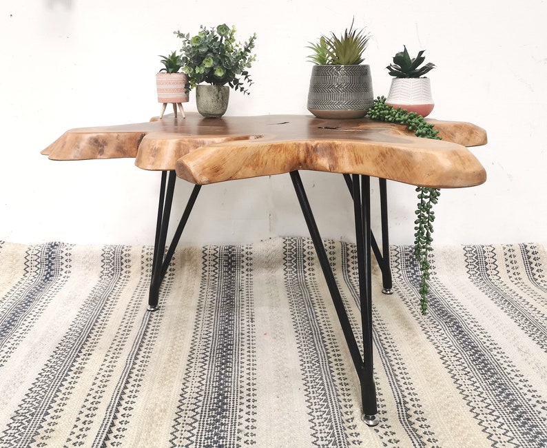 Pu&ograve; includere: Un tavolino da caff&egrave; in legno con un piano in legno vivo e gambe a forcina in metallo nero. Il tavolo &egrave; decorato con piante in vaso.