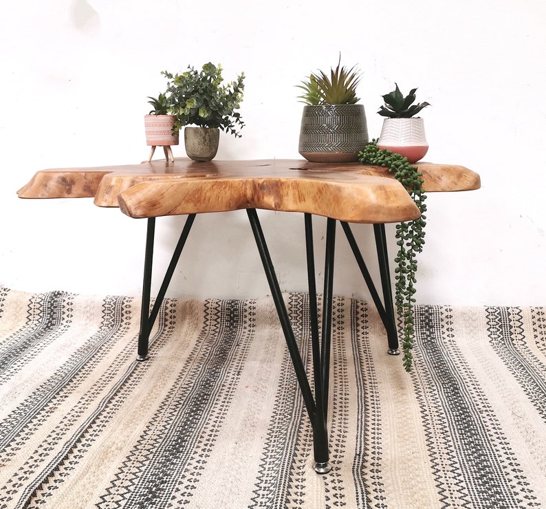 Pu&ograve; includere: Un tavolino da caff&egrave; in legno con un piano in legno vivo e gambe a forcina nere. Il tavolo &egrave; decorato con tre piante in vaso.