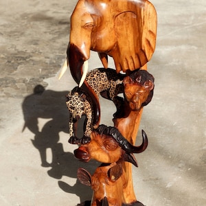 Duża, realistycznie rzeźbiona wieża z jasnobrązowego drewna oliwnego przedstawiająca pięć zwierząt. Wycinane na całej powierzchni głowy lamparta, lwa, bawoła, nosorożca i słonia.