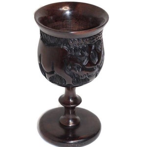 May include: A dark brown wooden goblet with intricate carvings. The goblet has a wide base and a tall, slender stem.