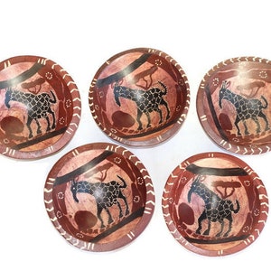 Puede incluir: Conjunto de cinco cuencos de madera con fondo rojo y marrón. Cada cuenco presenta una silueta negra de una jirafa con manchas blancas. Los cuencos tienen un borde decorativo blanco y marrón.