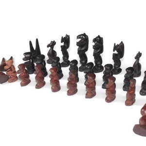 Può includere: Un set di scacchi completo con pezzi in legno intagliati in modo intricato. I pezzi sono in due colori, marrone scuro e marrone rossiccio, e sono disposti su una superficie bianca. Il set include pedoni, torri, cavalli, alfieri, una regina e un re.