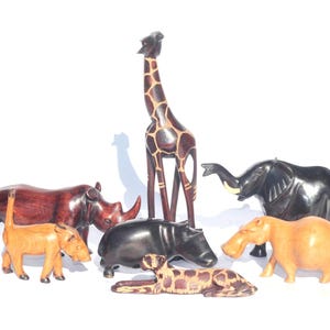 Könnte beinhalten: Ein Set aus Holztierfiguren, darunter eine Giraffe, ein Nashorn, ein Elefant, ein Flusspferd und ein Warzenschwein. Die Figuren sind handgeschnitzt und in natürlichen Holztönen bemalt.